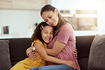 Mixed race single mother and daughter hugging in home living room. Smiling hispanic girl embracing and bonding with single parent in lounge. Happy affectionate woman and child together on weekend