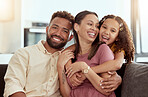 Mixed race parents enjoying weekend with daughter in home living room. Smiling hispanic girl hugging and bonding with mother and father in lounge. Happy affectionate couple sitting together with child