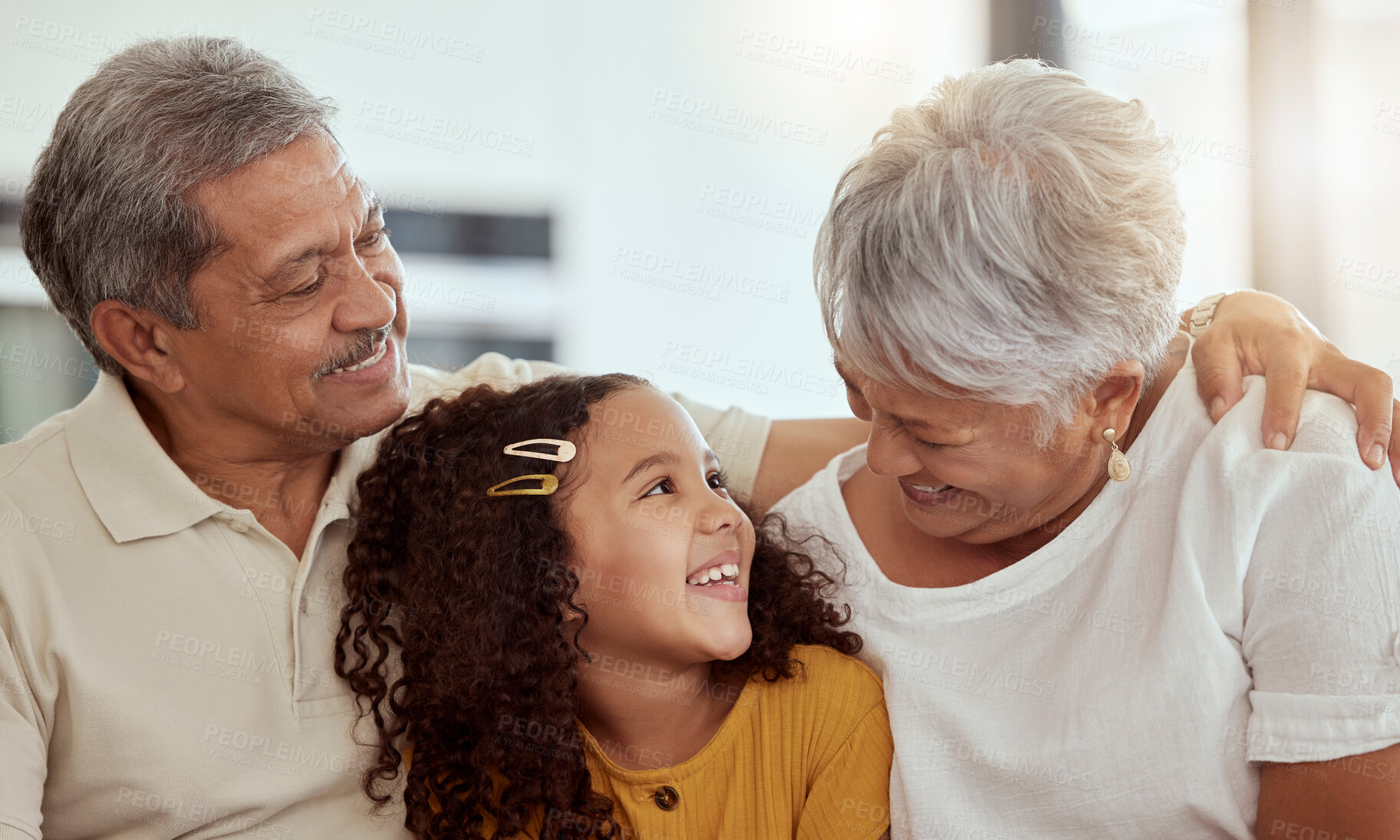 Buy stock photo Happy, grandparents and kid in home for love, comfort and support in living room. Elderly, girl child or hug on sofa for bonding, retirement visit and trust on weekend for care in relationship