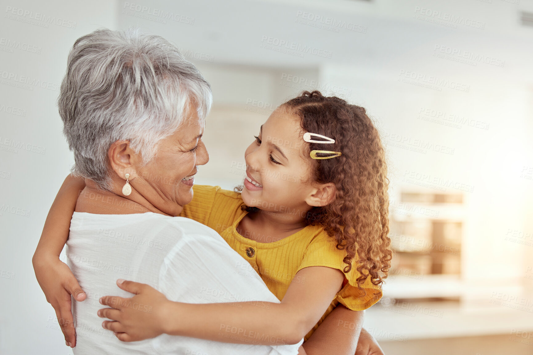 Buy stock photo Hugging, love and child with grandmother for bonding, care and connection together in home. Smile, family and girl kid embracing senior woman for support and relax in living room at house in Colombia