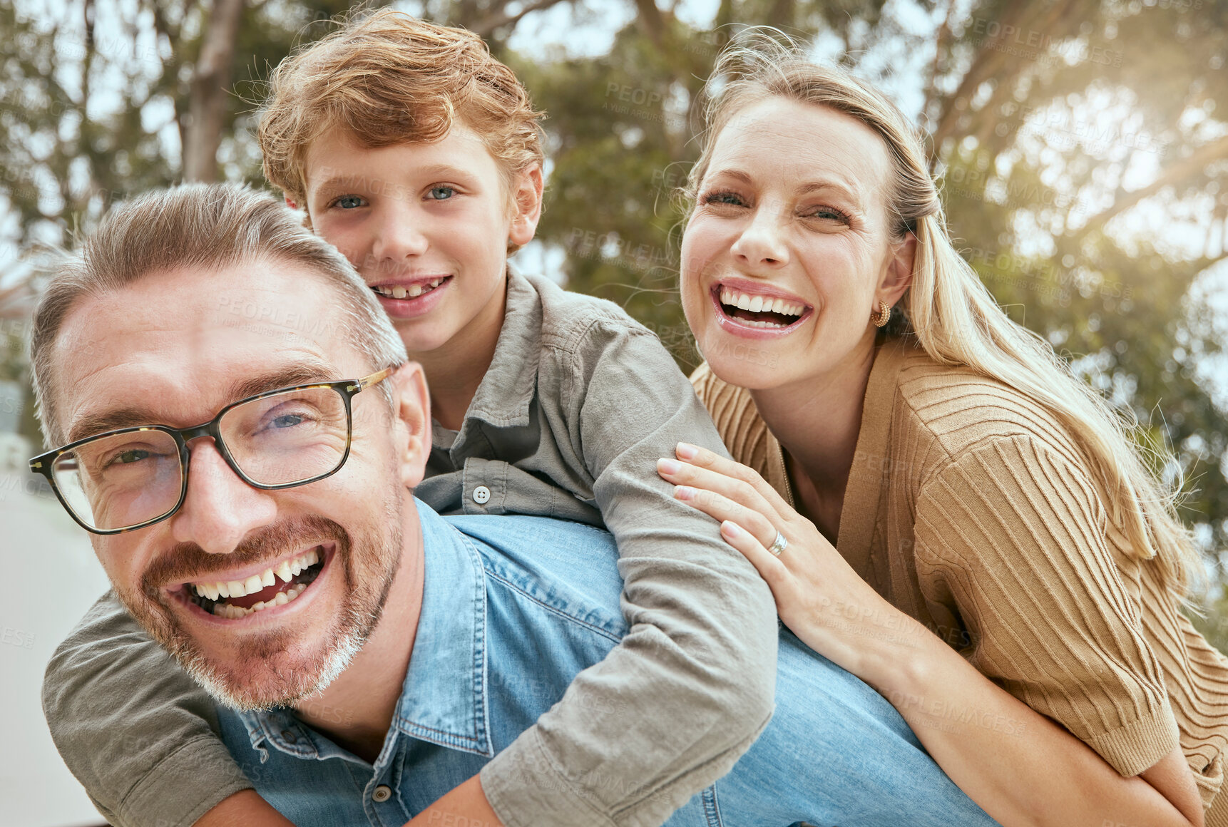 Buy stock photo Parents, child and piggyback with portrait outdoor for playful game, bonding and support of love in backyard. Smile, family and boy with trust, security and care from mom and dad with hug together