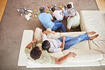 Overhead of a mixed race family bonding together while grandparents playing with the grandkids while the adult parents relax on the couch at home