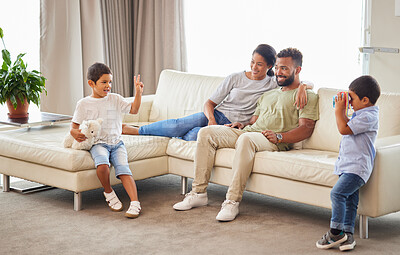 Buy stock photo Happy family, parents and kids with toy camera for picture, peace sign and bonding together on sofa. Mother, father and brothers play in home living room for game, love and care with stuffed animal