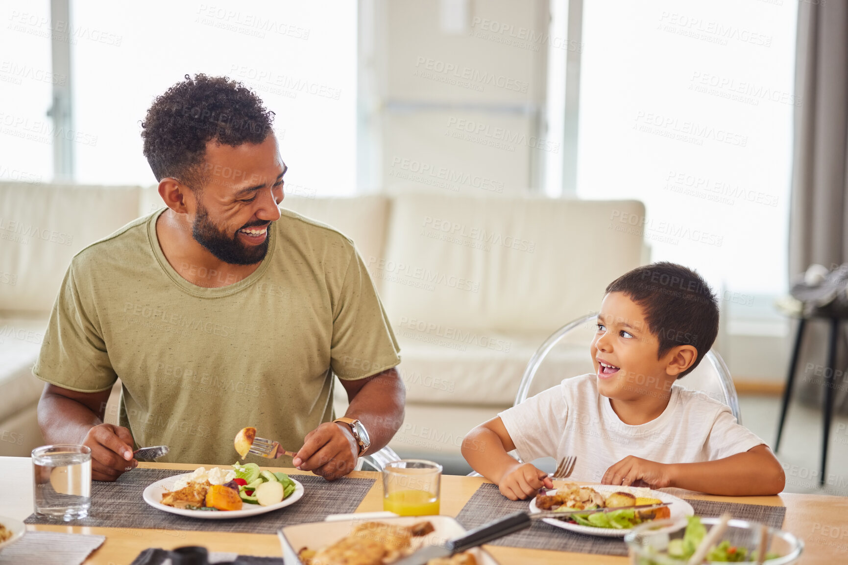 Buy stock photo Dad, kid and happy at table for lunch, healthy food and bonding in living room. Father, boy child and smile at home for nutrition, family time and Sunday meal with funny story or joking together