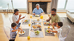 Overhead view of a mixed race family sitting at a table having lunch  in the lounge at home. Hispanic grandparents having a meal with their kids and grandkids at home