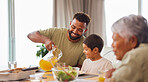 Closeup of a mixed race male and his son enjoying some food at the a table during lunch at home in the lounge. Hispanic father smiling and eating alongside his son at home