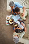 Overhead closeup of a little mixed race boy blowing the candles on a cake at a birthday party with his little brother, parents  and grandparents smiling and watching. Cute hispanic boy celebrating his birthday with his family at home