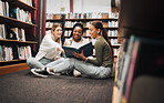 University, students and women in library with book working on, researching and looking up information for group research project. College, student diversity and friends working on homework together 