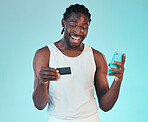 Black man, happy with smartphone and credit card, e commerce and payment success or win on blue background. Fintech, online shopping and website discount, giveaway with customer experience in studio