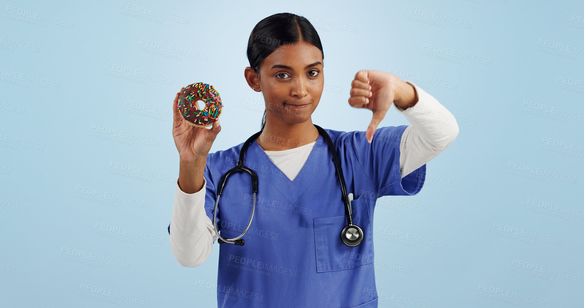 Buy stock photo Woman, portrait and doctor with thumbs down, donut and bad review for diet on a blue studio background. Female person rejection, emoji or sign with chocolate dessert, diabetes and high blood sugar