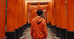 Man, outdoor and walk by shinto torii gate, back and culture for thinking, ideas and nature in forest. Person, statue and memory on spiritual journey, Fushimi Inari shrine and architecture in Kyoto