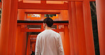 Man, torii gate and Japanese culture on trip, travel and traditional landmark for spirituality. Buddhism, monument and back of person in Kyoto, worship and prayer or peace in Fushimi Inari Shinto