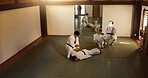 Aikido students, bow or learning martial arts in dojo for practice, body movement or self defense. Combat demonstration, Japanese people or black belt training workout for fighting education or class