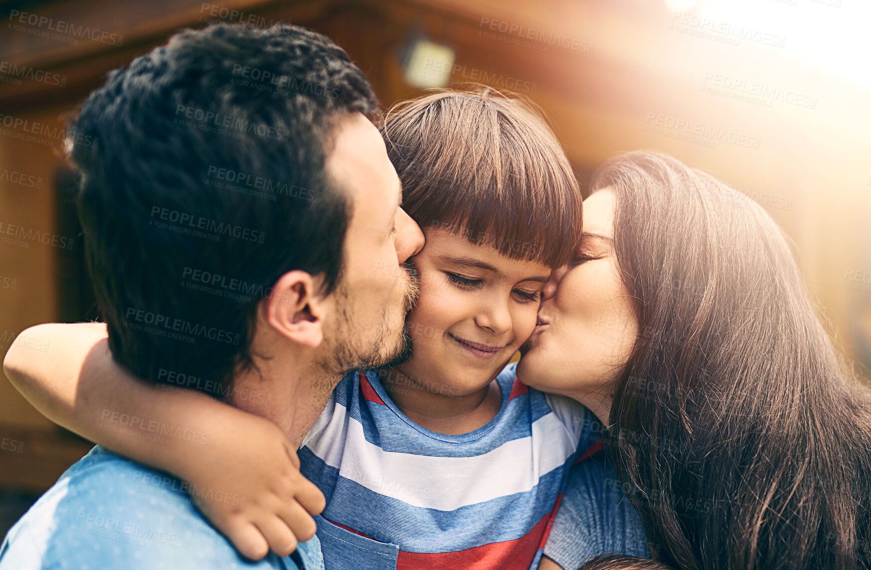 Buy stock photo Happy family, love and parents kiss child outdoor for care, bonding and relax together. Smile, father and mother with kid at backyard to hug for support, connection and healthy relationship by house