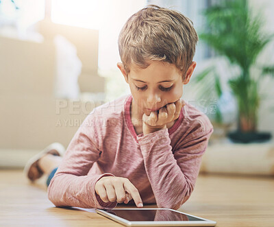 Buy stock photo Kid, tablet and home for relax browsing, elearning and educational games with boy in living room. Tech, video app and streaming cartoon or child development, lounge floor and online in apartment 