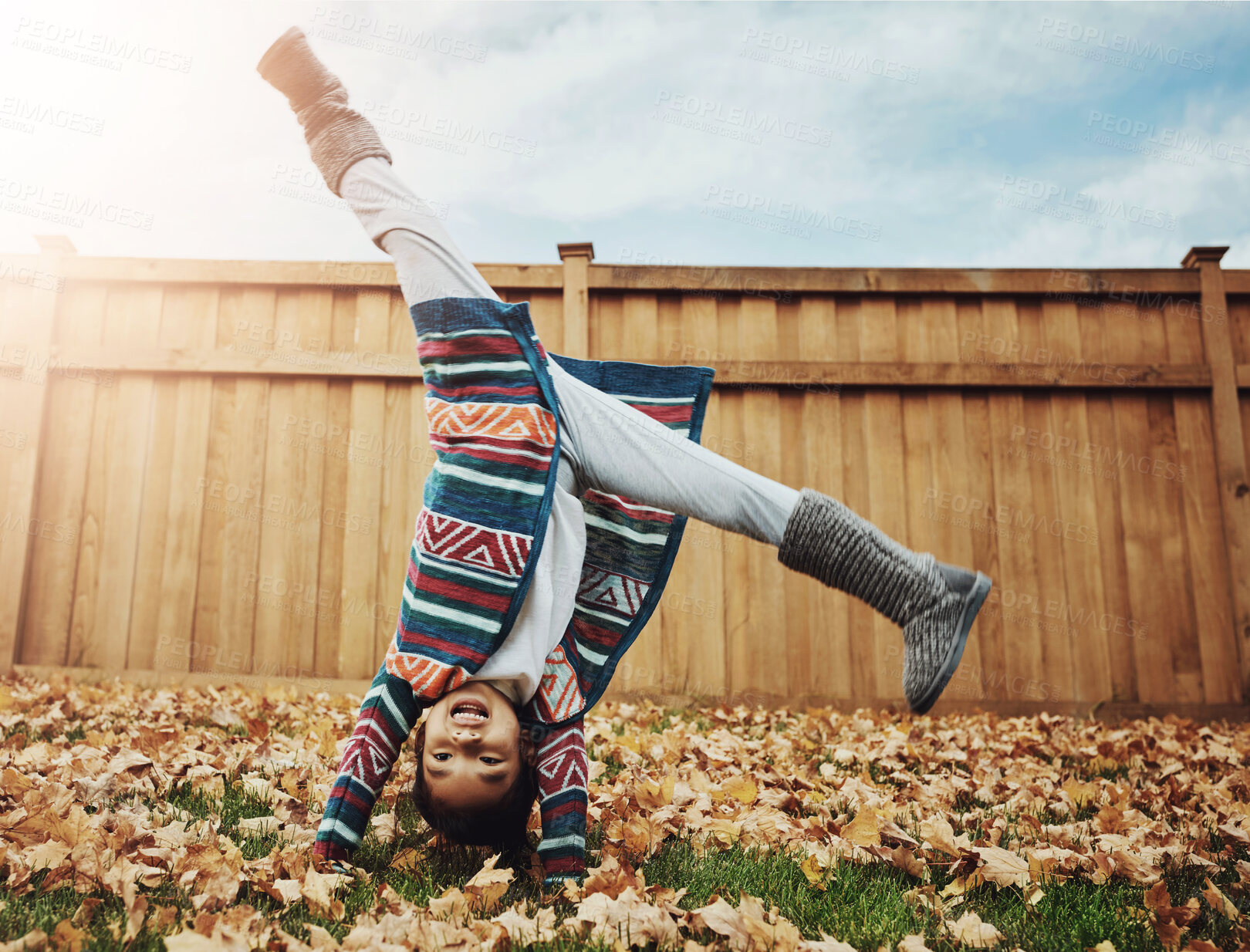 Buy stock photo Girl, child and playing cartwheel outdoor in backyard for autumn fun, energy and flexible in development. Person, childhood and handstand on leaves in garden with activity, game and happy in home