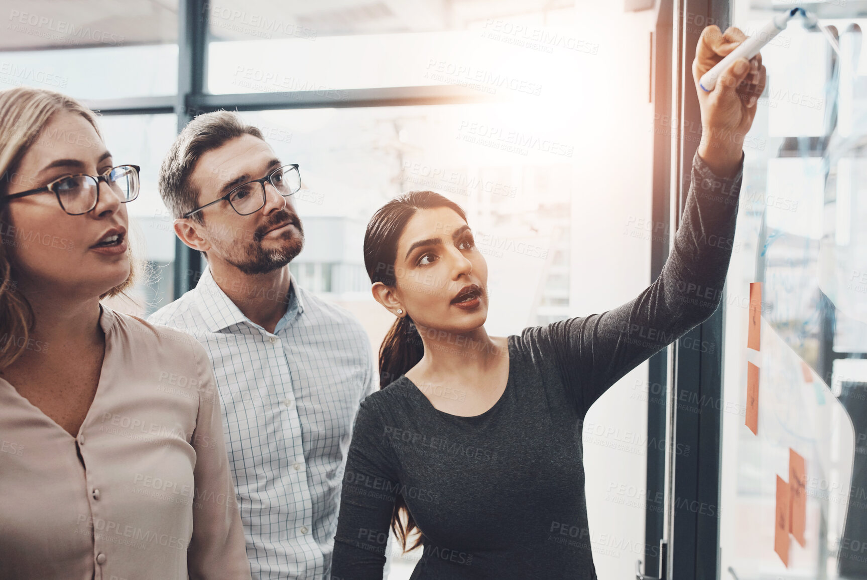 Buy stock photo Woman, team and meeting with writing on board with sticky notes, discussion and planning with brainstorming. Coach, training and group by glass wall, synergy or collaboration with strategy in office