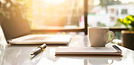 Home office, notebook and laptop on table with coffee, sunrise glow or interior design. Remote work, technology or cup in workspace for productivity, small business or appointment schedule in morning