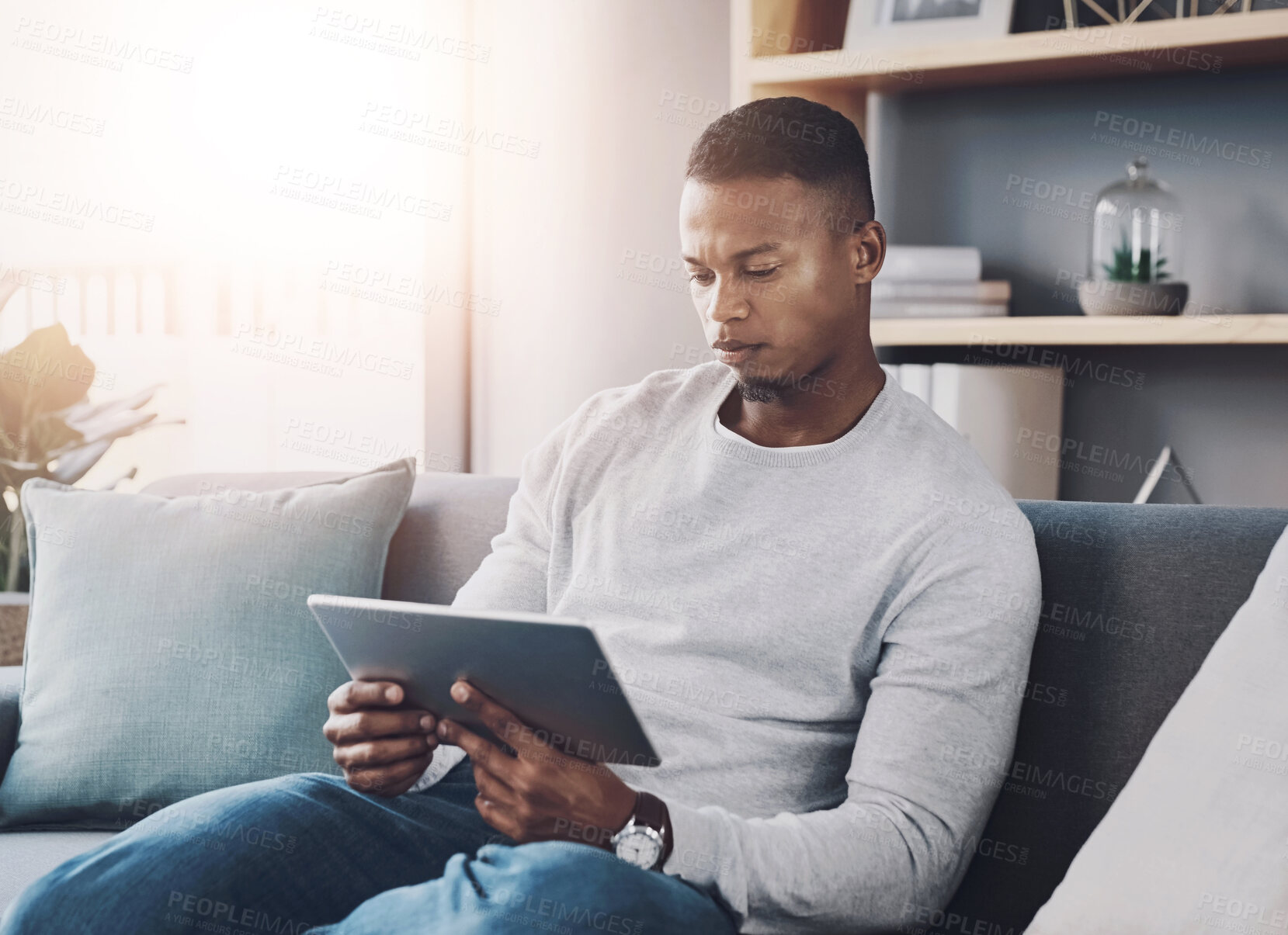 Buy stock photo Black man, tablet and reading on sofa in home, living room and relax with ebook, streaming or application. Person, digital touchscreen and watch on couch with film, video and subscription in house