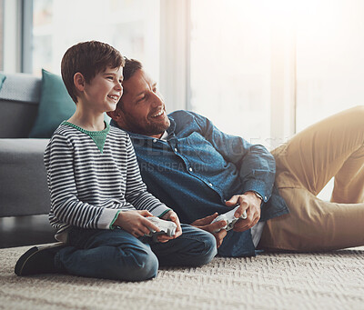 Buy stock photo Happy father, relax and playing games with child on console for entertainment or bonding on floor at home. Dad, son or kid with smile and enjoying esports together on carpet with controller at house