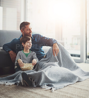 Buy stock photo Popcorn, laugh and dad watching tv with child on floor in living room at family home. Blanket, bonding and father with kid for streaming movie, film or show with snack in lounge at house in Canada.