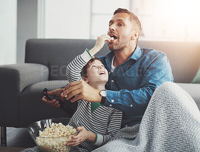 Buy stock photo Man, tv remote and kid with popcorn by sofa for entertainment, snack and watching cartoon together. Family, father and son with feeding in living room for love, care and streaming of show at home