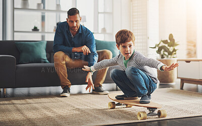 Buy stock photo Father, child and skateboard with balance in living room for activity, leisure or skill at home. Dad, kid or little boy riding on board with wheels for bonding, holiday or weekend together at house