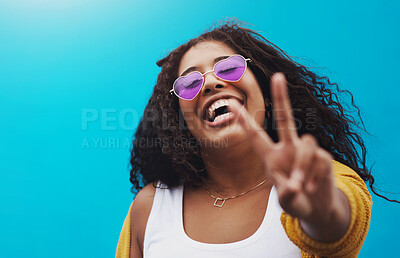 Buy stock photo Portrait, happy and woman with peace sign in studio for gen z fashion, heart glasses and aesthetic style. Excited, girl and cool v icon with trendy eyewear, emoji and sunglasses on blue background