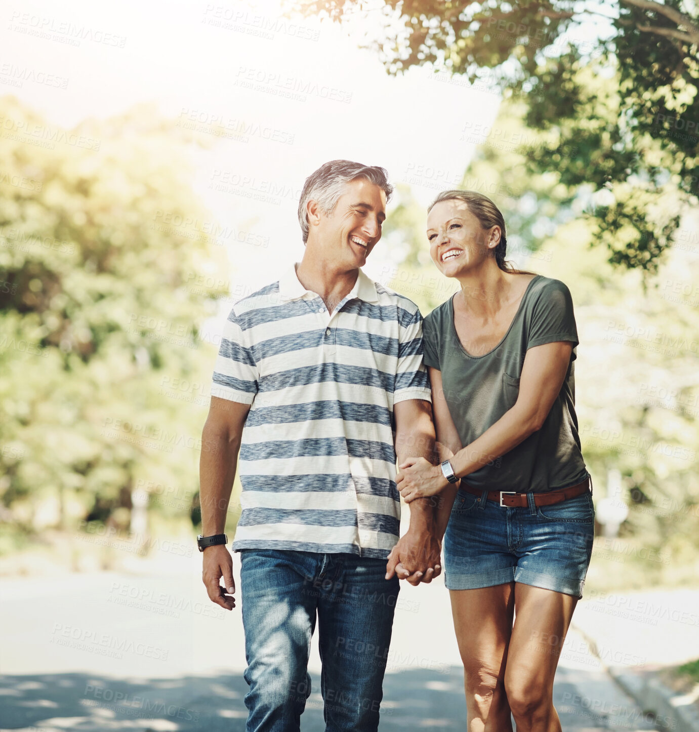 Buy stock photo Happy, holding hands and couple in park walking for bonding, relationship and love outdoors. Nature, marriage and man and woman laugh in street for romance, affection and relax on weekend together