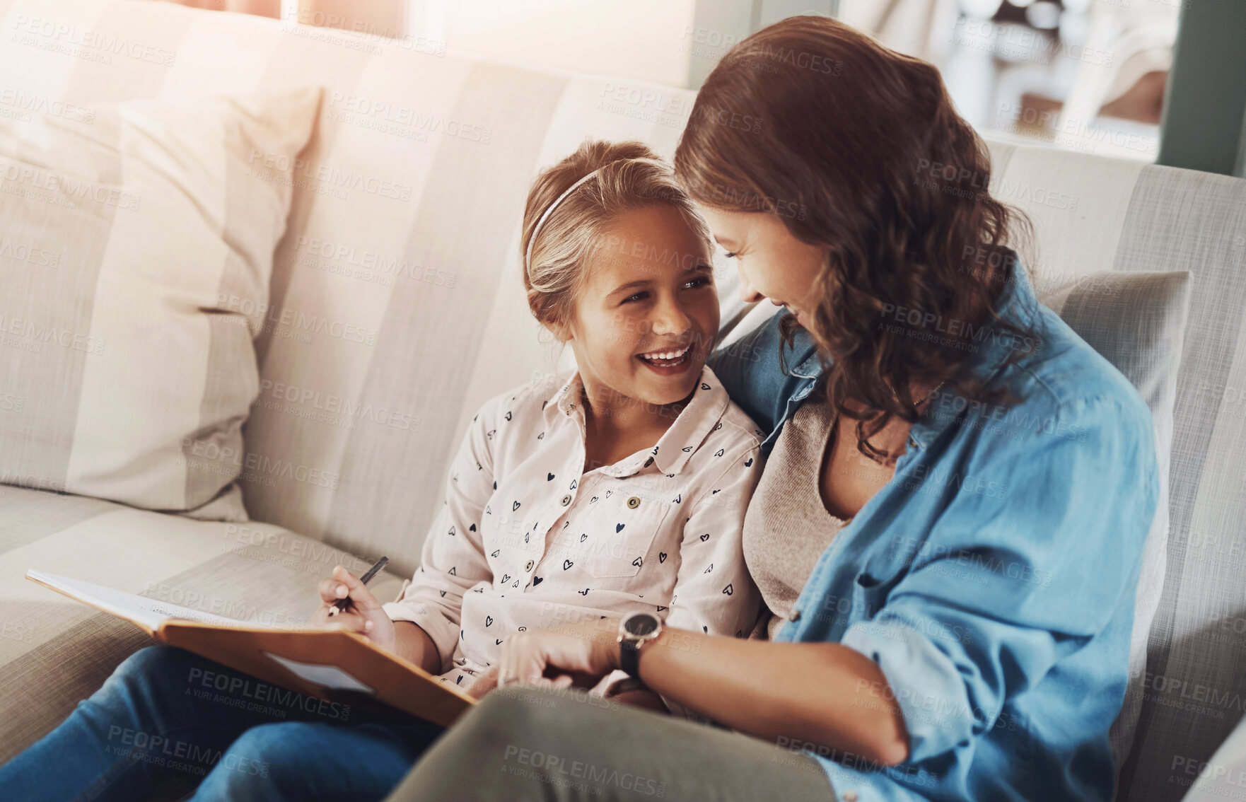 Buy stock photo Mother, girl and book on sofa for writing, learning and happy with bonding, help and care in family home. Woman, mom and child with education, drawing and guide for advice with homework in Munich