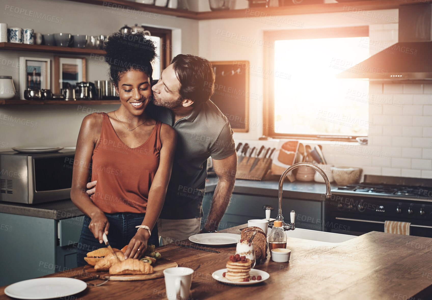 Buy stock photo Happy, couple and kiss in kitchen with breakfast for morning affection, compassion and connection with care. Interracial lovers, man and woman in home with love for bonding, relationship and together