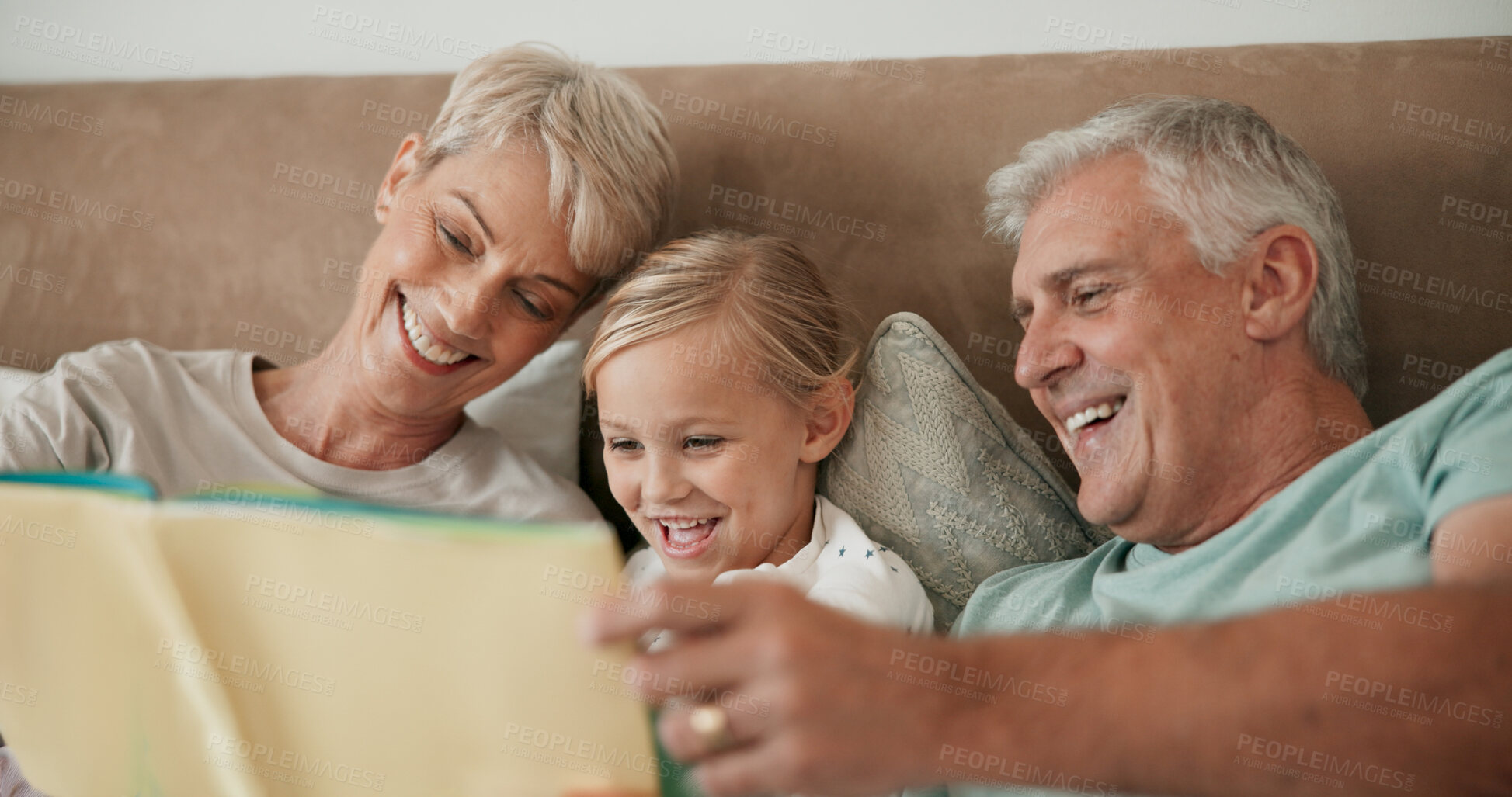 Buy stock photo Grandparents, girl and reading book in bed to relax, literature and literacy for bonding at sleepover. Home, grandchild and people learning for love, language and grandma or grandpa for fairytale