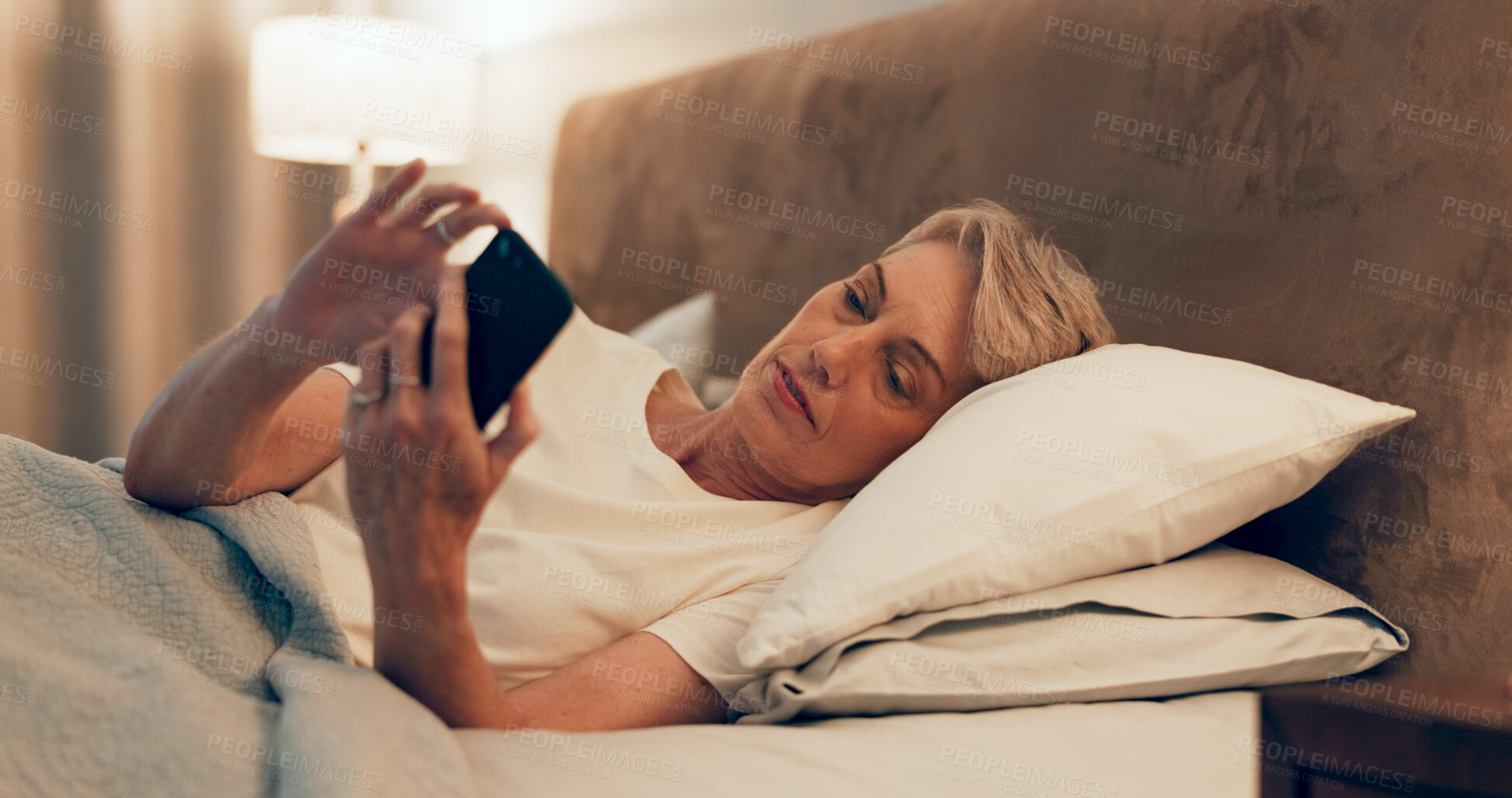 Buy stock photo Reading, bed and mature woman with cellphone for online blog on insomnia, sleep apnea or relaxing. Communication, night and senior female person networking with email on phone in bedroom at home.