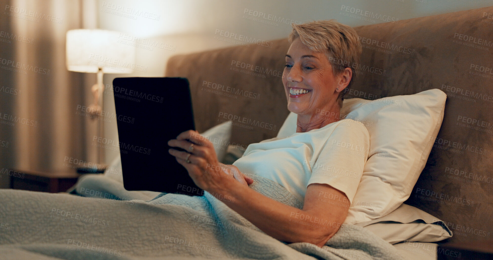 Buy stock photo Happy, mature woman and bedroom with tablet for streaming, entertainment and online in home. Senior person, cheerful and relax with laughing, joy and fun for rest, break and connection on technology