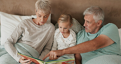 Buy stock photo Grandparents, girl and reading fiction in bed for storytelling, literature and bonding at sleepover. Home, grandchild and people learning together for love, book and grandma or grandpa for fairytale