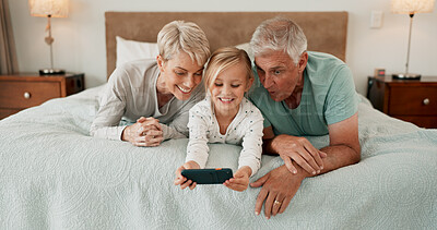 Buy stock photo Grandparents, happy and mobile phone with grandchild in bedroom for growth, development and gaming in home. Girl, playing and tech for learning, selfie and fun as kid with senior people for bonding