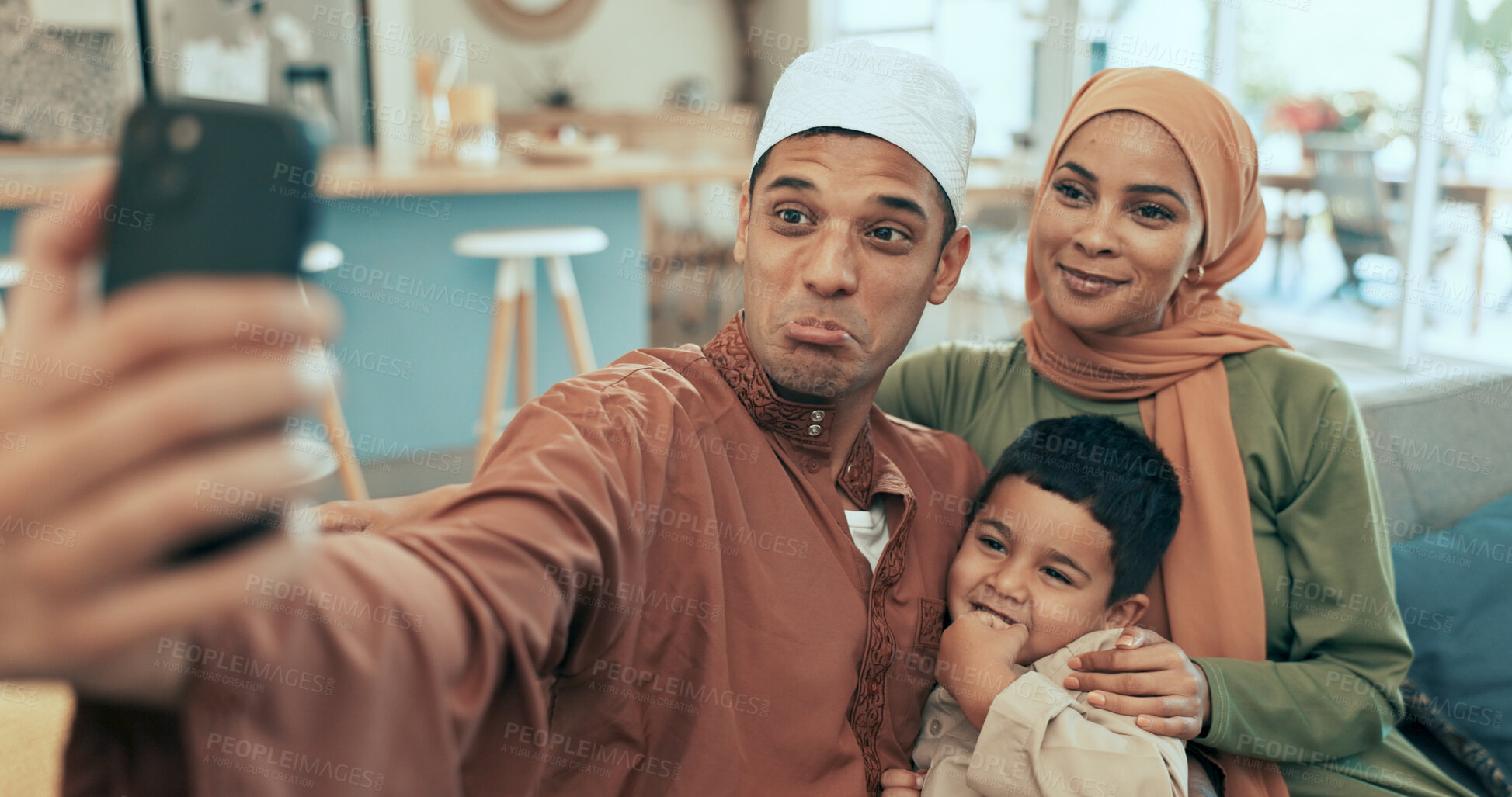 Buy stock photo Selfie, happy and muslim family on sofa in home for Eid celebration with faith in living room. Goofy, love and islam parents with boy child for photography picture on ramadan with hijab and kofia.