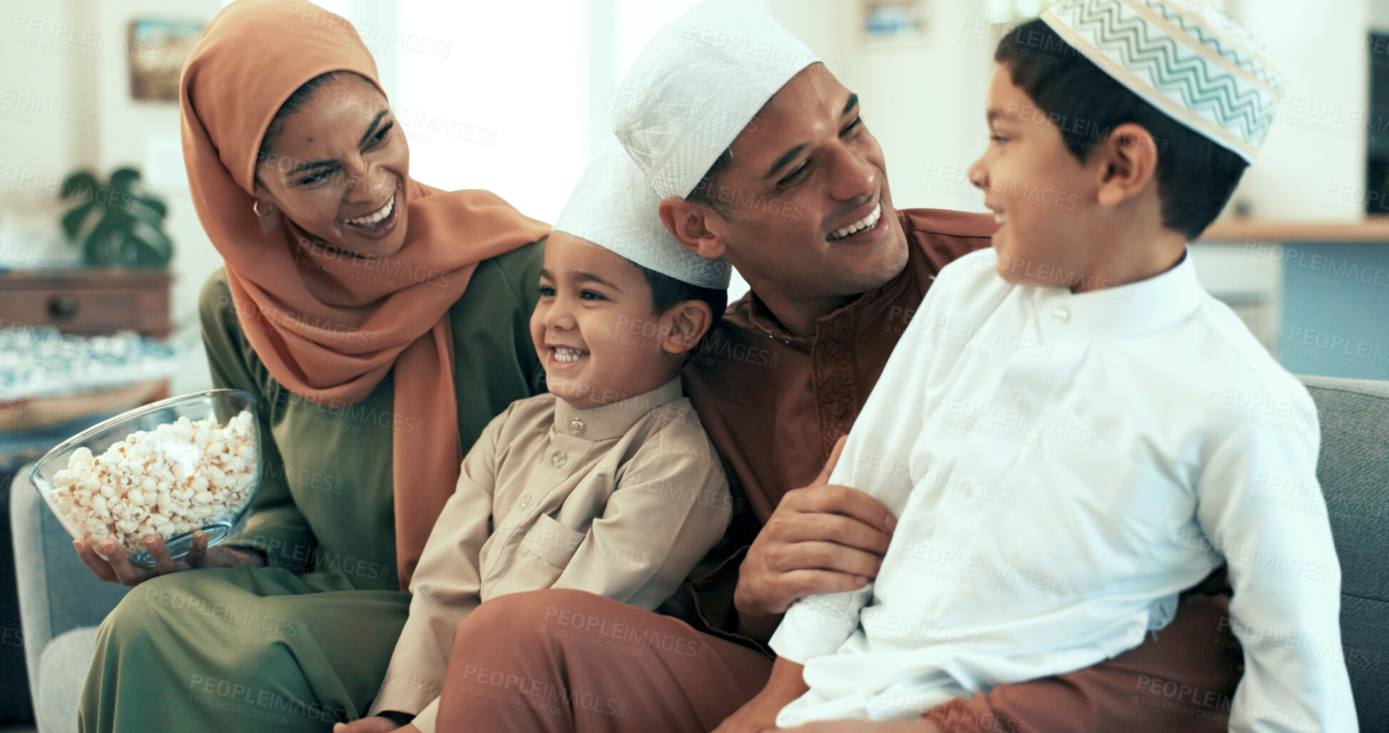 Buy stock photo Muslim family, popcorn and watching tv on sofa in living room of home for bonding or comedy. Laughing, television or video with Islamic mother, father and kids in apartment for movie streaming