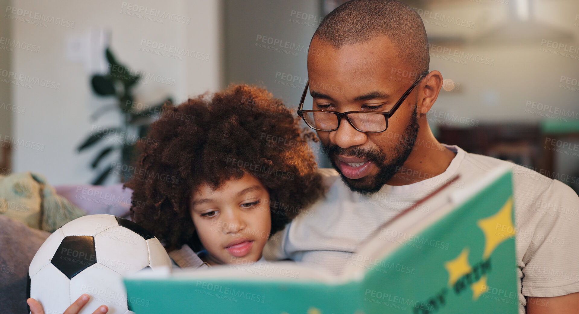 Buy stock photo African man, son and story book on sofa with football, listening and bonding in family house. Father, boy and reading with care, fantasy and relax with love, literature and learning in living room