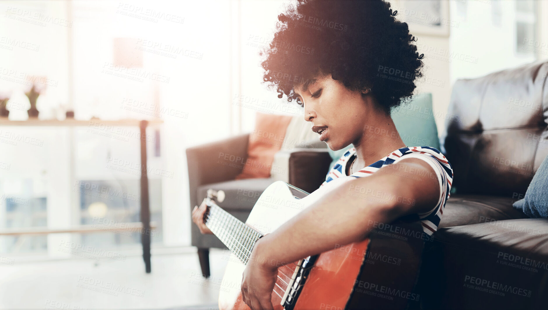 Buy stock photo Shot of a young woman playing the guitar while sitting at home