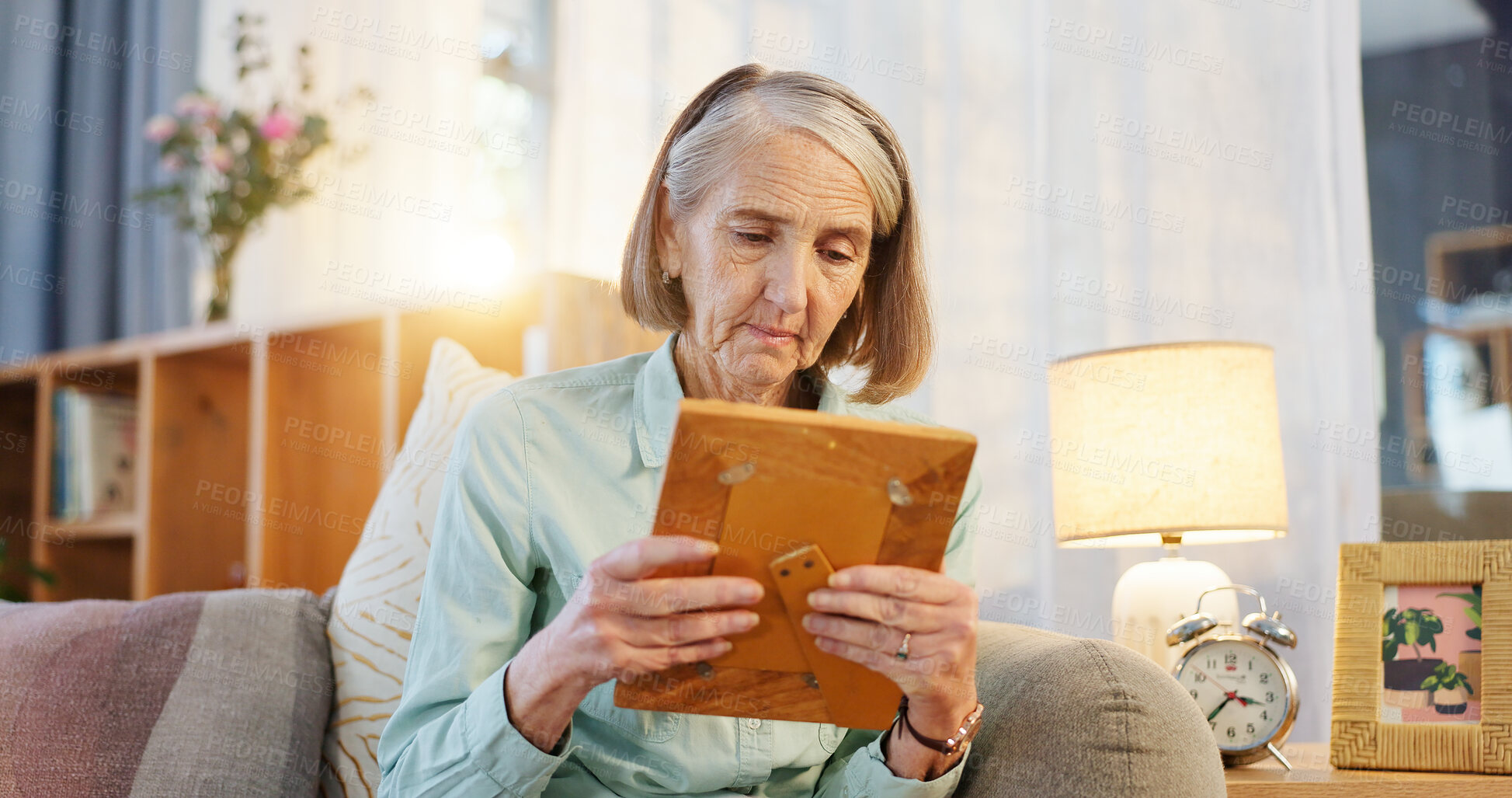 Buy stock photo Sad, senior woman and picture frame for memory, nostalgia and remember history in home living room. Retirement, photo and past of missing person with grief, lonely and mourning family member on sofa