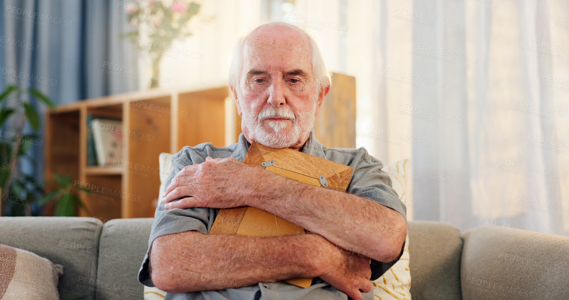 Buy stock photo Sad, senior man and thinking with picture frame for memory, nostalgia and remember in home. Retirement, past and hug photo of missing person with grief, lonely and depression on sofa in living room