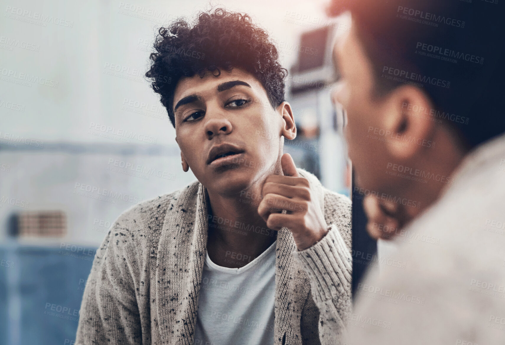 Buy stock photo Shot of a handsome young man inspecting his face in the bathroom mirror