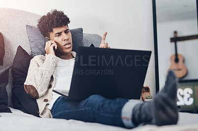 Buy stock photo Shot of a young man using a smartphone and laptop on the bed at home