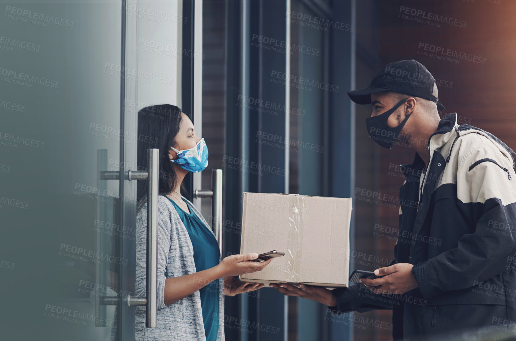 Buy stock photo Shot of a masked young woman receiving a delivery at home