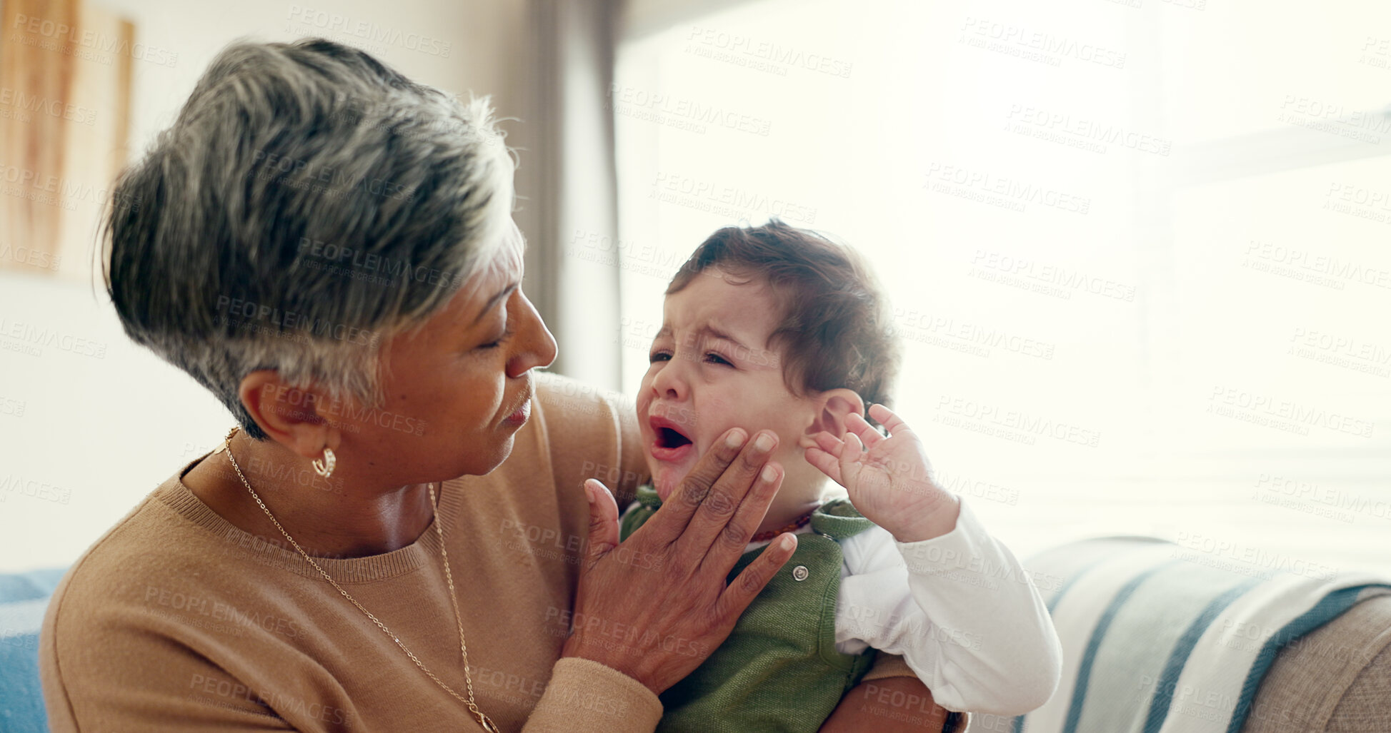 Buy stock photo House, grandma and hug for crying baby, sad and comfort in living room, emotions and love. Apartment, granny and senior woman with infant, boy and tears with care, frustrated and kindness in lounge