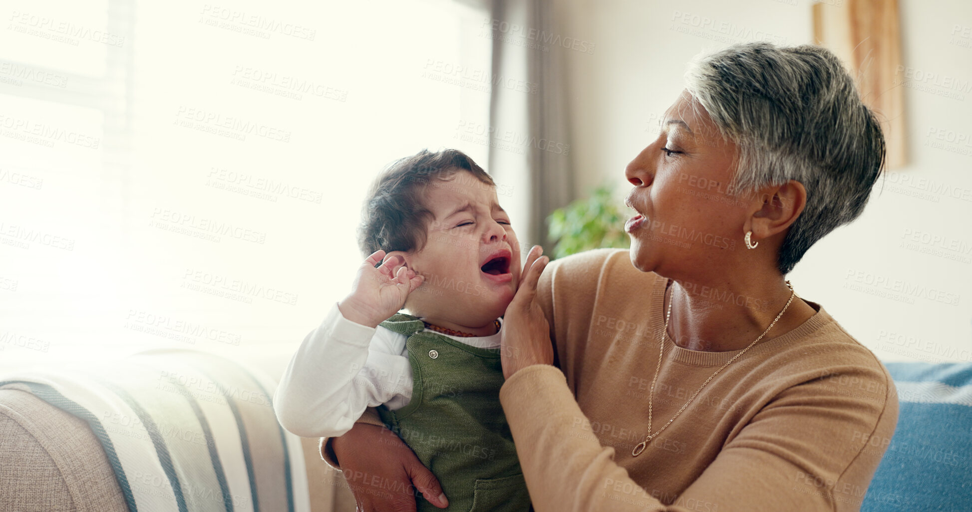 Buy stock photo Home, grandmother and hug for crying baby, sad and comfort in living room, family and love. Apartment, granny and senior woman with infant, boy and tears with care, compassion and kindness in lounge