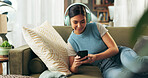 Woman, home and smartphone with headphones on sofa for music, playlist and entertainment. Female person, couch and smile in living room for audio or radio and streaming podcast for fun and relax