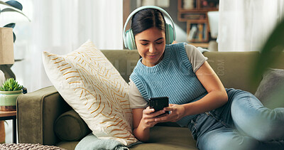 Buy stock photo Woman, home and smartphone with headphones on sofa for music, playlist and entertainment. Female person, couch and smile in living room for audio or radio and streaming podcast for fun and relax