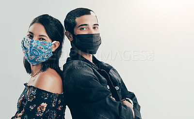 Buy stock photo Studio shot of a masked young man and woman posing against a grey background